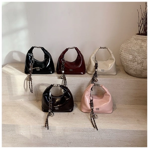 Detailed close-up of glossy patent leather crescent bags in various colors on stone steps