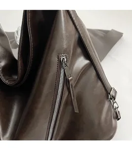Detail of high-quality smooth silver zipper and dark brown leather texture on tote bag