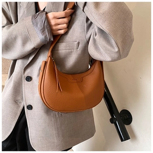 Dettaglio della borsa hobo in pelle caramello con logo goffrato e fibbia in metallo