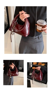 Detail of burgundy patent leather crescent bag with woven strap and bell charm accent