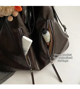 Detail view of large dark brown leather tote with front zipper pockets and plush charm