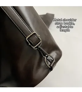 Macro shot of adjustable gun-tone shoulder strap buckle on dark brown leather tote bag