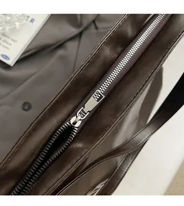 Detailed close-up of smooth silver metal zipper on a premium brown tote bag
