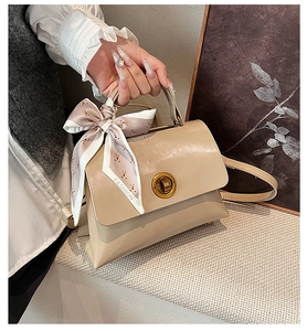 Detail of beige tote bag with gold twist lock and a fashion polka dot silk scarf handle