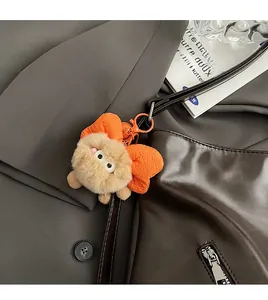 Brown plush cartoon charm with orange bow and carabiner on dark leather tote bag