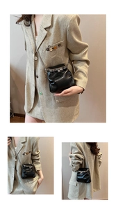 Detail of black pleated crossbody bag with silver clasp closure and thin metal chain strap
