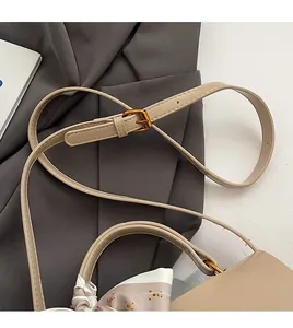 Detail of adjustable shoulder strap with gold buckle and decorative silk scarf on khaki bag