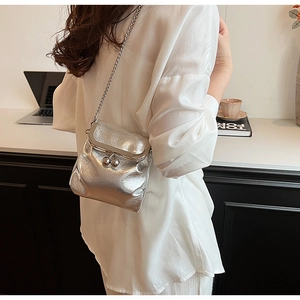 Mini borsa a secchiello argento con catena metallica e texture a pieghe in un set lifestyle