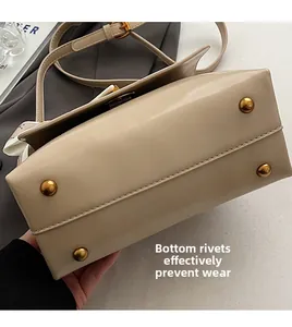 Detail view of the beige handbag bottom featuring four gold-tone protective metal studs