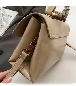 Detail of beige shoulder bag with gold hardware and silk scarf wrapped handle