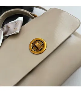 Close-up of beige leather handbag with gold twist lock and printed teddy bear scarf