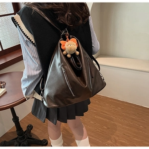 Detail of vintage dark brown leather backpack with metal zippers and plush charm