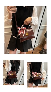 Detail of dark red vintage oil wax leather bag with golden lock and silk scarf handle