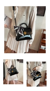 Close-up of black oil wax leather handbag with golden twist lock and silk scarf detail