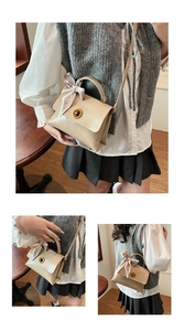 Detail of cream leather messenger tote with gold twist lock and printed silk scarf