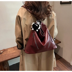 Burgundy faux leather backpack with plush charm and metal zipper on model back