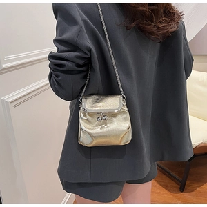 Mini borsa a secchiello argento con catena indossata da modella con blazer grigio