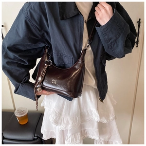 Close-up of polished dark brown hobo bag with metallic logo and knot charm detail