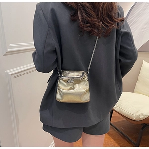 Close-up of a mini gold metallic frame bag with a stylish chain strap and sphere clasp