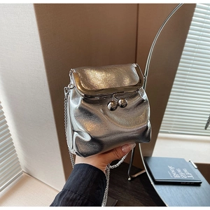 Détail d'un sac bandoulière argenté métallisé avec fermoir vintage et bandoulière chaîne