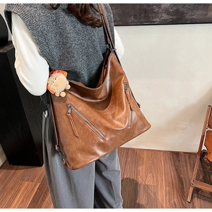 Detail view of a vintage dark brown tote bag with metal zippers and adjustable strap