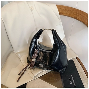 Detailed macro view of black patent leather bag texture with silver metal handle buckle