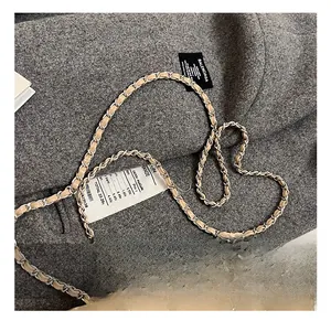 Close-up of beige quilted leather bag with silver metal and leather interwoven chain strap