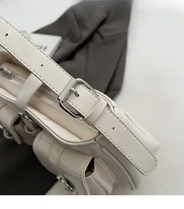 Detailaufnahme der weißen Umhängetasche aus genarbtem Leder mit silbernen Schnallen