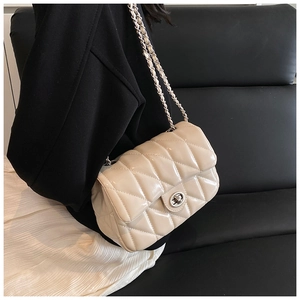 Quilted crossbody bag in beige leather worn by a model in a stylish black suit