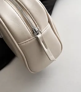 Makro-Detail des glatten silbernen Metall-Reißverschlusses an cremeweißer Leder-Handtasche