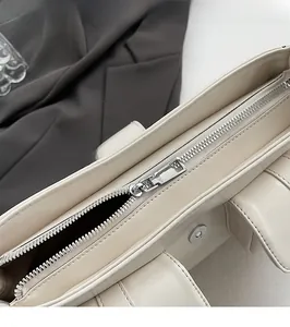 Nahaufnahme von silbernem Reißverschluss und Präzisionsnähten an beiger PU-Handtasche