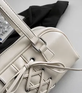 Detail der cremefarbenen Ledertasche mit dekorativer Schnürung und silbernen Metallschnallen