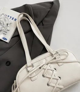 Detail der cremeweißen Ledertasche mit Kreuzband-Design und silberfarbenen Beschlägen