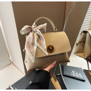Detail of khaki leather handbag with gold round lock and decorative fashion silk scarf