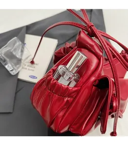 Detail of red glossy pleated bag side pocket showing functional perfume storage