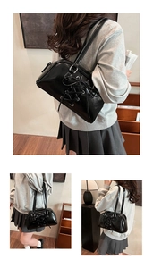Detailansicht der schwarzen Lackleder-Schultertasche mit schickem Schnür-Schleifen-Design.