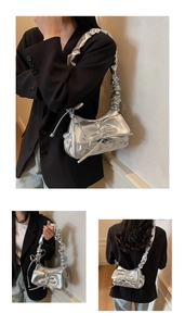 Dettaglio borsa metallizzata argento con tracolla a pieghe e fiocco decorativo chic