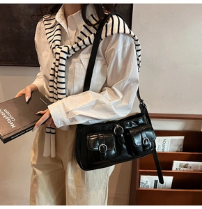 Details einer schwarzen glänzenden Umhängetasche mit Schnallen im Retro-Stil