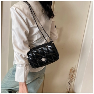 Close-up of black quilted leather crossbody bag with silver chain and metal twist lock
