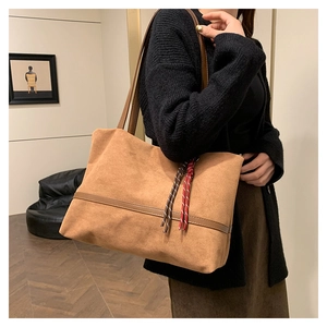 Sac cabas en velours marron avec détail tressé porté par un mannequin dans un décor épuré