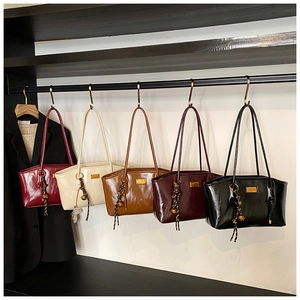 Detail shot of five colors of vintage oil wax leather tote bags with metal bell charms