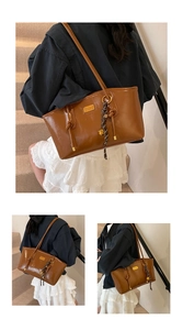 Detail of retro oil wax leather tote bag with gold logo and woven rope charm
