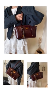 Close-up of deep wine red glossy tote bag with gold hardware and tassel charm detail