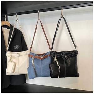 Detail view of denim tote bags in white, blue, and black with small pouch charms