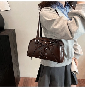 Detailansicht einer braunen Lackleder-Umhängetasche im Retro-Stil mit schicker Schleife.