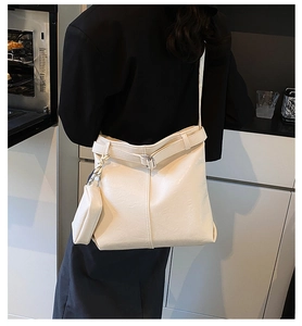 Close-up of a cream white leather tote bag with a small matching pouch and decorative buckle