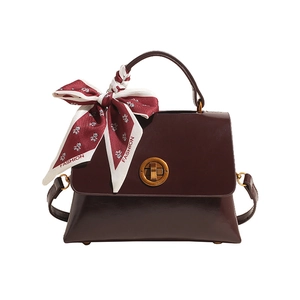 Classic burgundy leather handbag with vintage metal clasp and decorative silk scarf