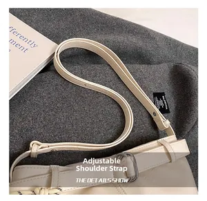 Detail of adjustable off-white leather shoulder strap with silver metal buckles on tote bag