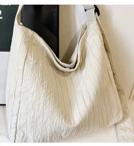 Détail du sac cabas blanc cassé avec texture plissée verticale et large bandoulière souple