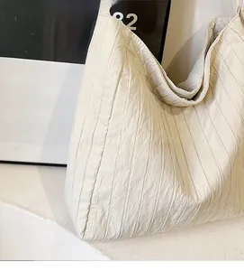 Détail d'un grand sac cabas plissé beige avec texture verticale et tissu doux et léger